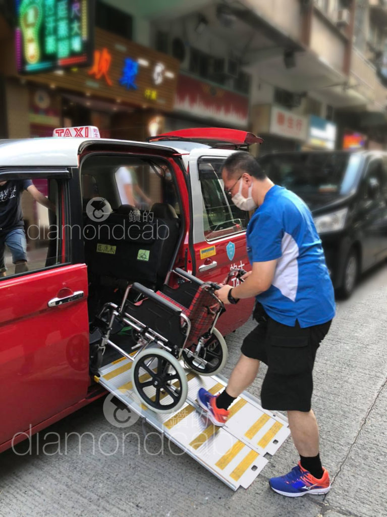 a man pushing a wheel chair out of a DiamondCab taxi. 一個男人從 「鑽的」的士裡推著輪椅出來。