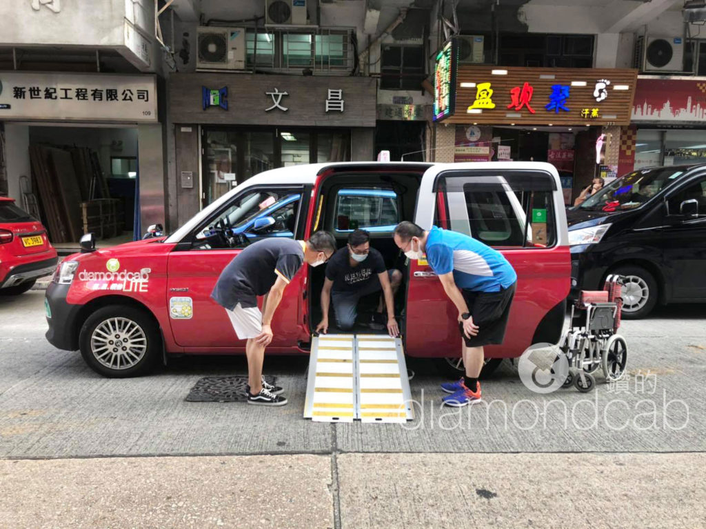 Three men lowering a ramp for a DiamondCab taxi. 三名男子正降下「鑽的」的士的斜板。