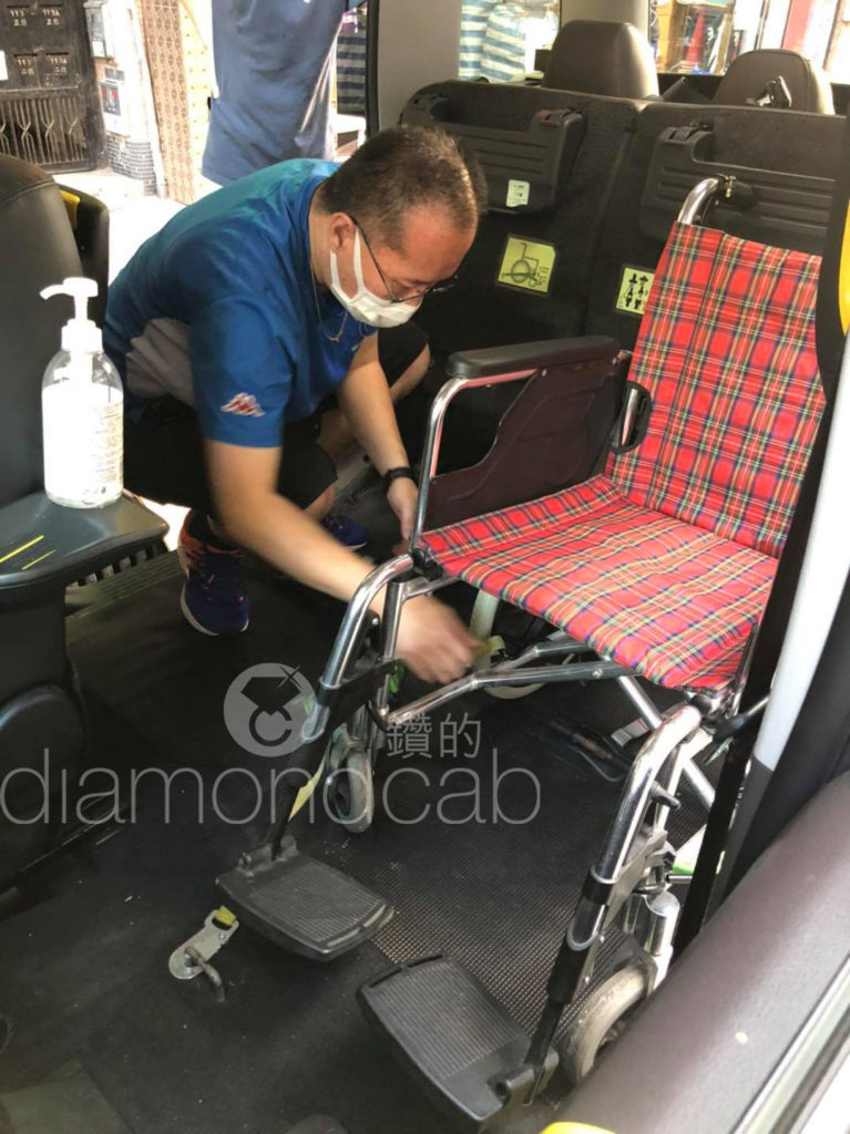 a man tying a wheelchair inside of a DiamondCab taxi.
一名男子於「鑽的」的士緊綁輪椅。
