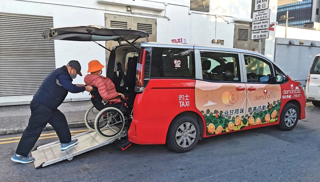 A taxi driver tying a man in wheelchair inside of a DiamondCab taxi. 一名的士司機於「鑽的」的士上爲一名輪椅人士緊綁輪椅。